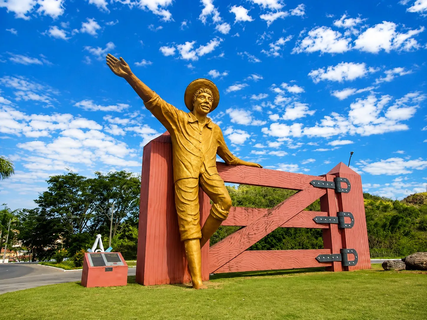 Monumento ao Menino da Porteira em Ouro Fino, estátua dourada junto à porteira vermelha